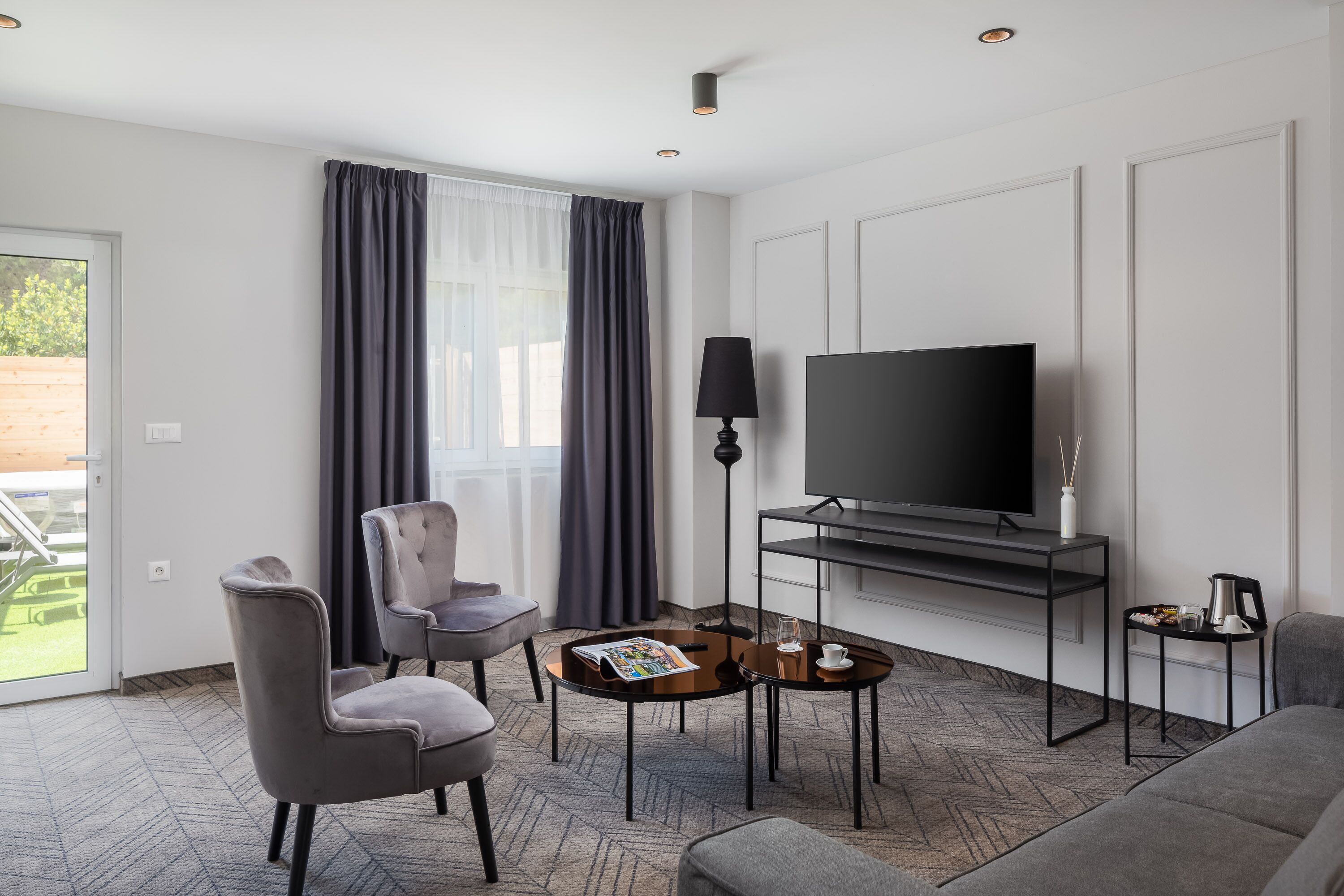 Une chambre d’hôtel moderne équipée d’un téléviseur à écran plat, de deux fauteuils, d’une table basse et d’un canapé.
