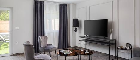 Une chambre d’hôtel moderne équipée d’un téléviseur à écran plat, de deux fauteuils, d’une table basse et d’un canapé.