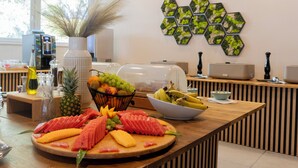 Een ontbijtbuffet met verschillende soorten fruit en een koffieapparaat op de achtergrond.
