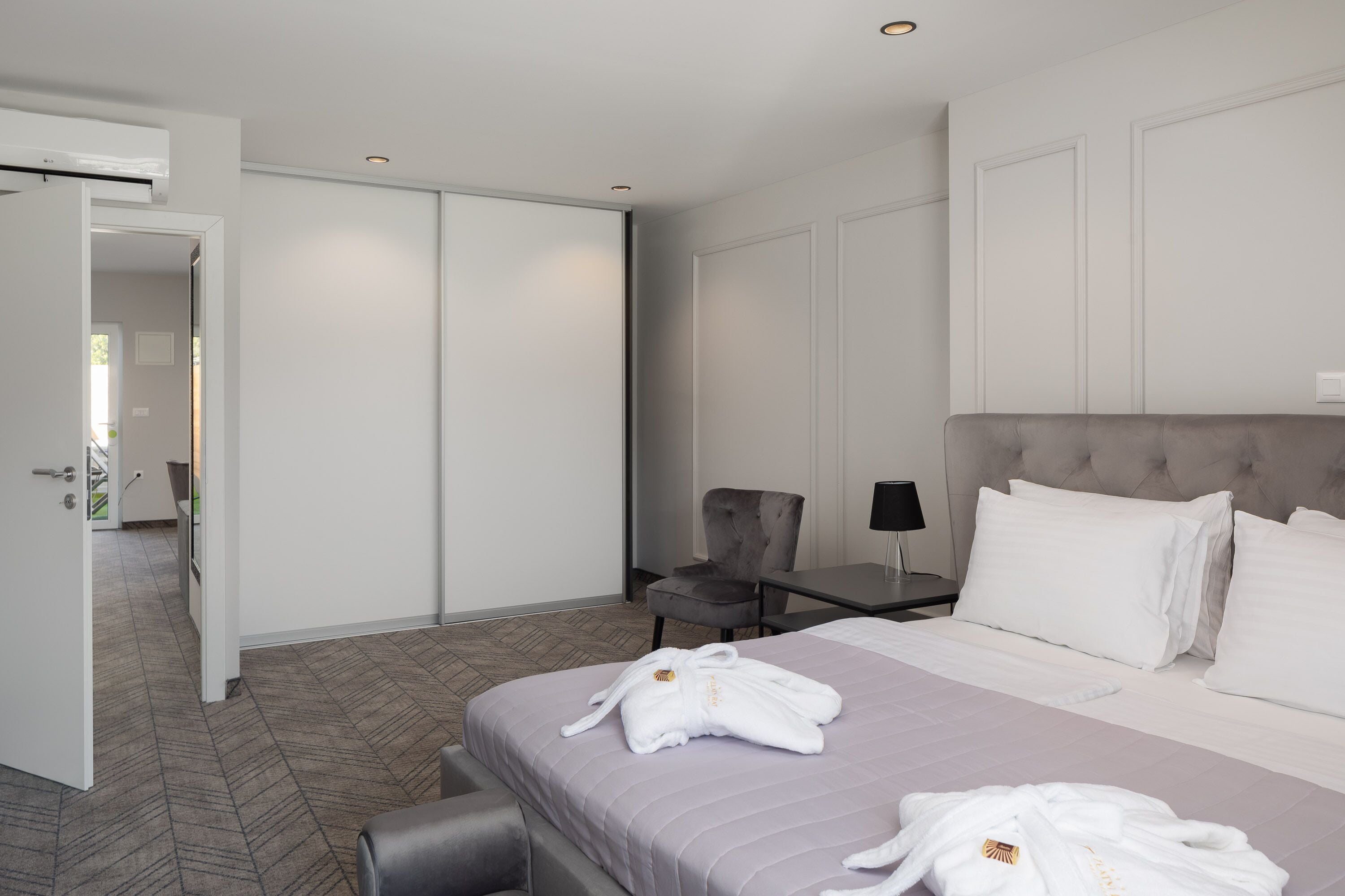 Una habitación de hotel con una cama, una silla, un escritorio y un armario.