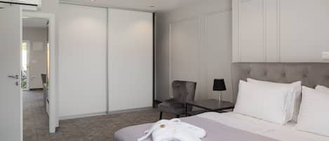 A hotel room with a bed, a chair, a desk, and a wardrobe.