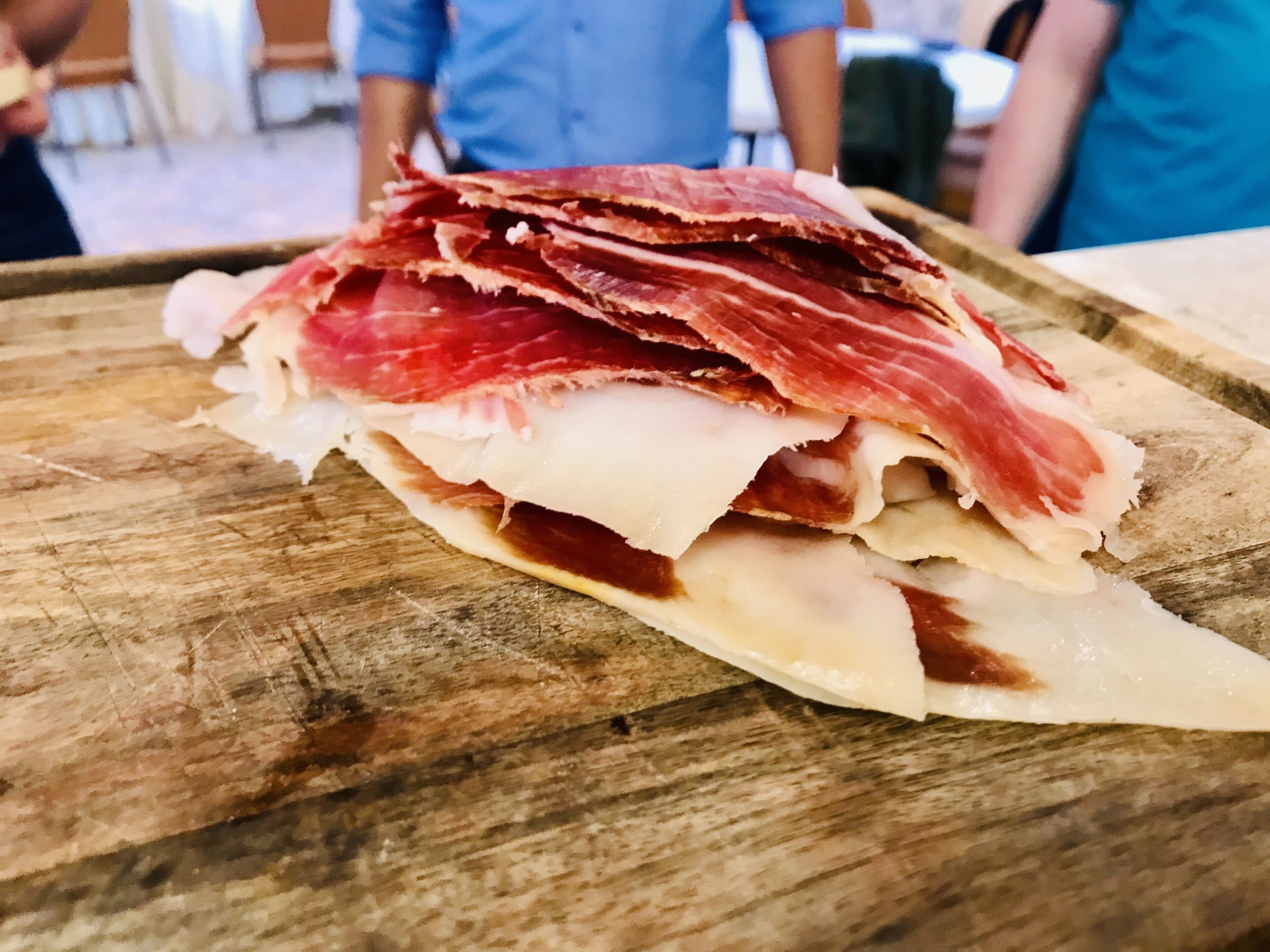 Una tabla de madera con carne curada y queso en rodajas.