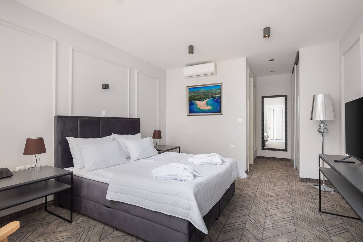 Une chambre d’hôtel moderne avec un grand lit, un bureau, une télévision et un tableau au mur.