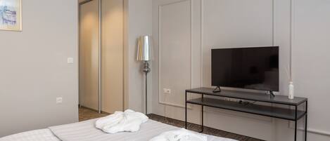 Una camera d'albergo con un letto, una TV su un supporto, una lampada e un quadro appeso al muro.