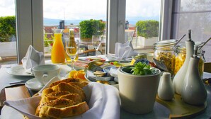 A breakfast table with various food items, a glass of orange juice, and a view of the outdoors. - Villa Azzurra (Bol)