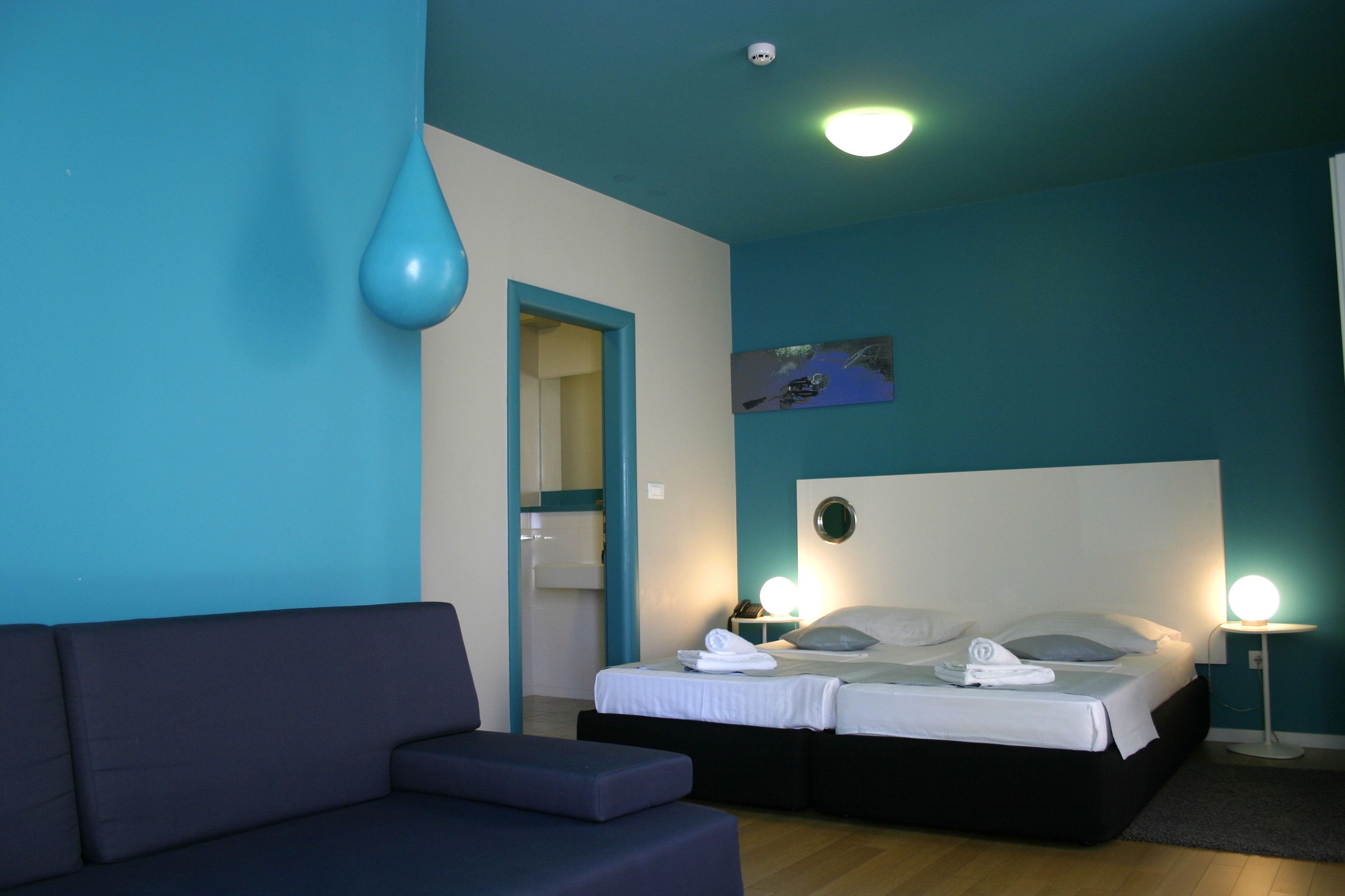 Ein Schlafzimmer mit einem Bett, einem Nachttisch, einer Lampe, einem Sofa und einer Tür.