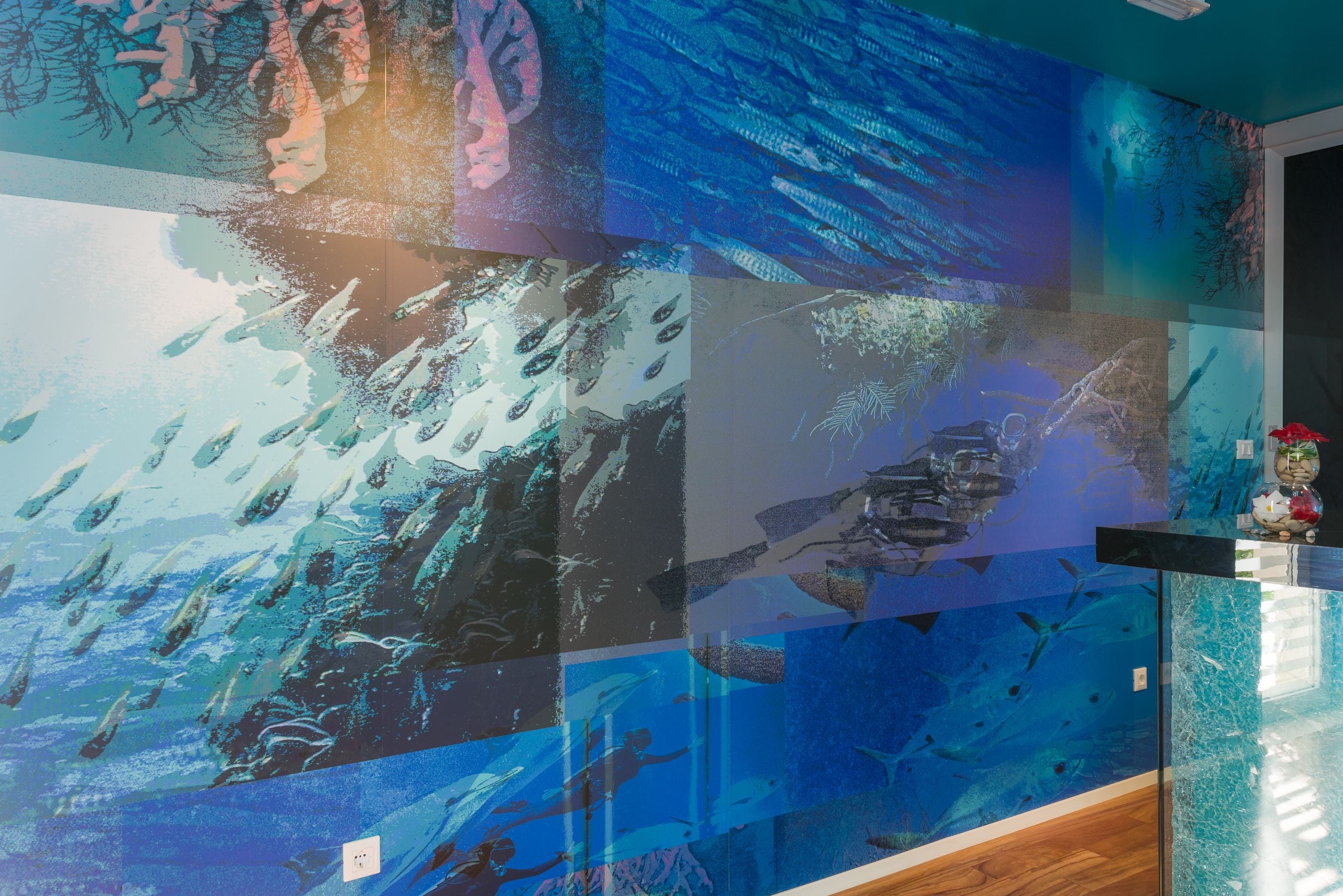 Eine Wand mit einem Mosaik aus Unterwasserlandschaften, darunter Fische und Korallen.