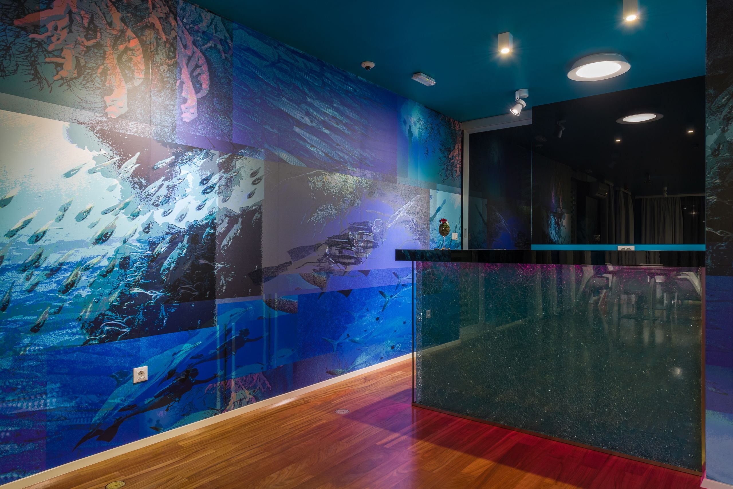 A modern interior with a large aquarium wall, wooden flooring, and a glass partition.