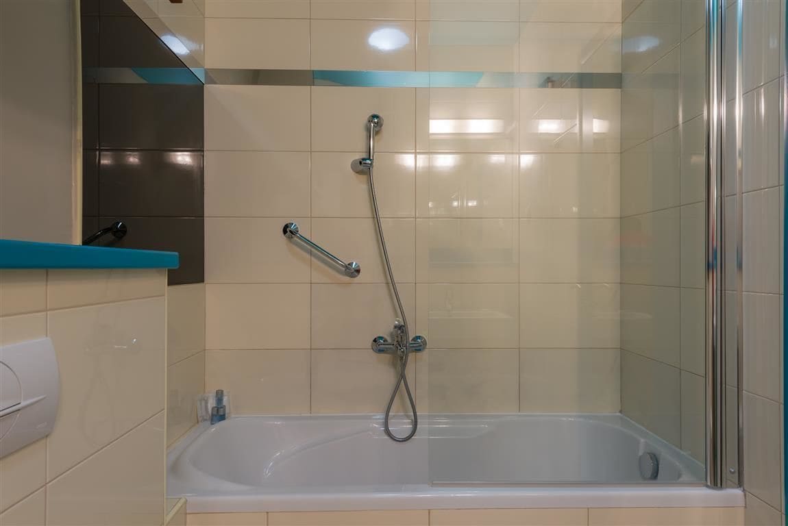 Un baño moderno con ducha de vidrio, una bañera blanca y un estante azul.