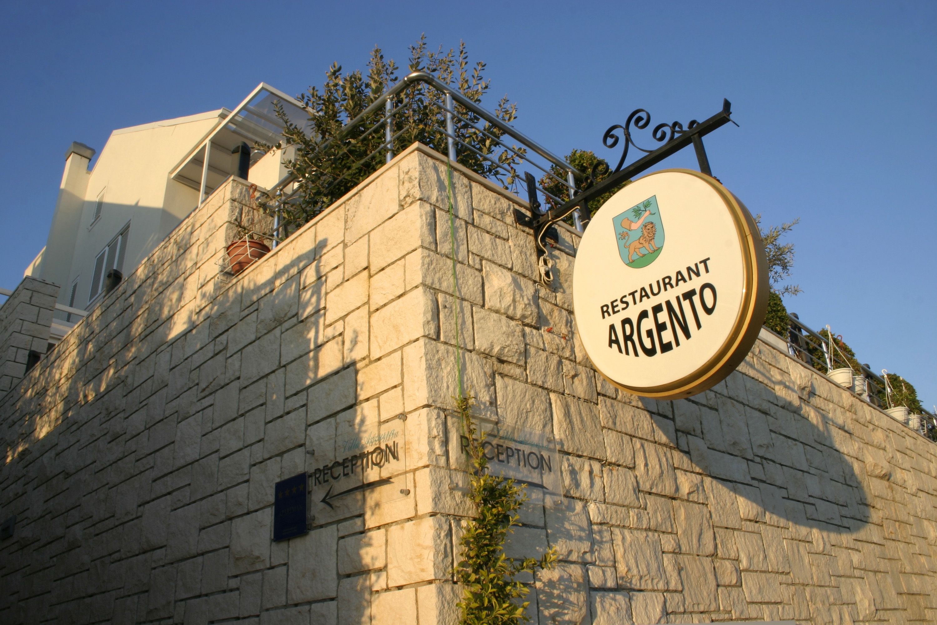 Un edificio in pietra con un cartello che indica 'Restaurant Argento' e una zona reception.