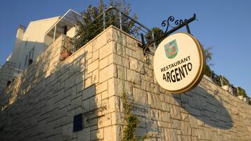 Un bâtiment en pierre avec une enseigne indiquant « Restaurant Argento » et un espace d’accueil.