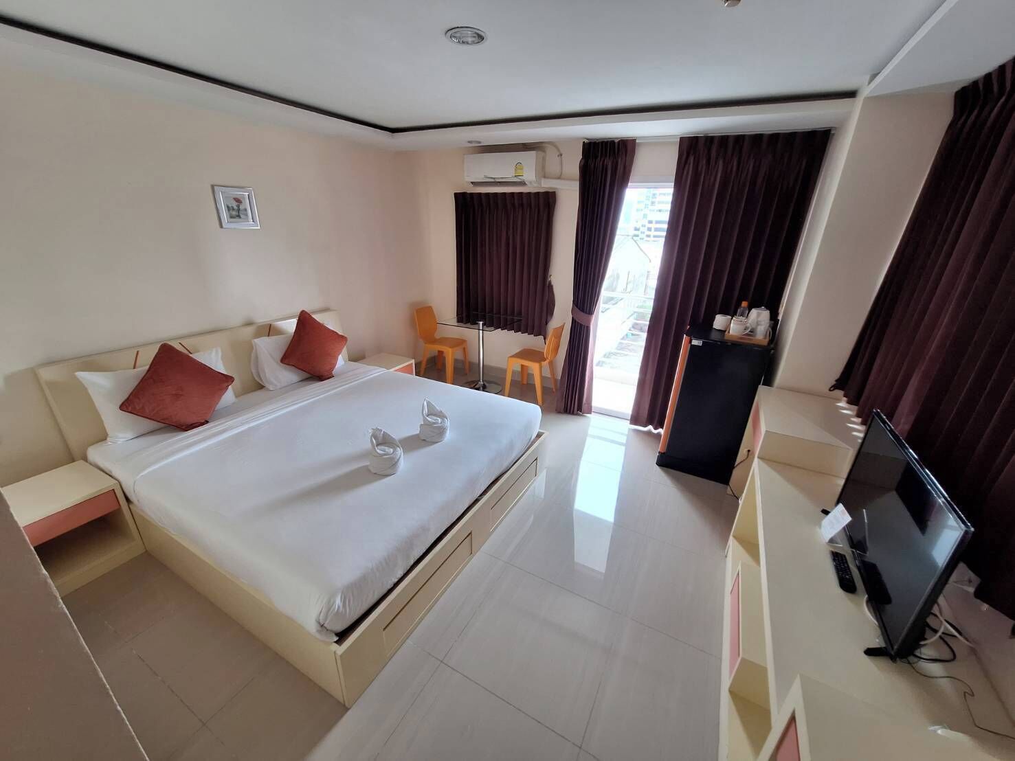 A hotel room with a large bed, a desk, a chair, and a television.