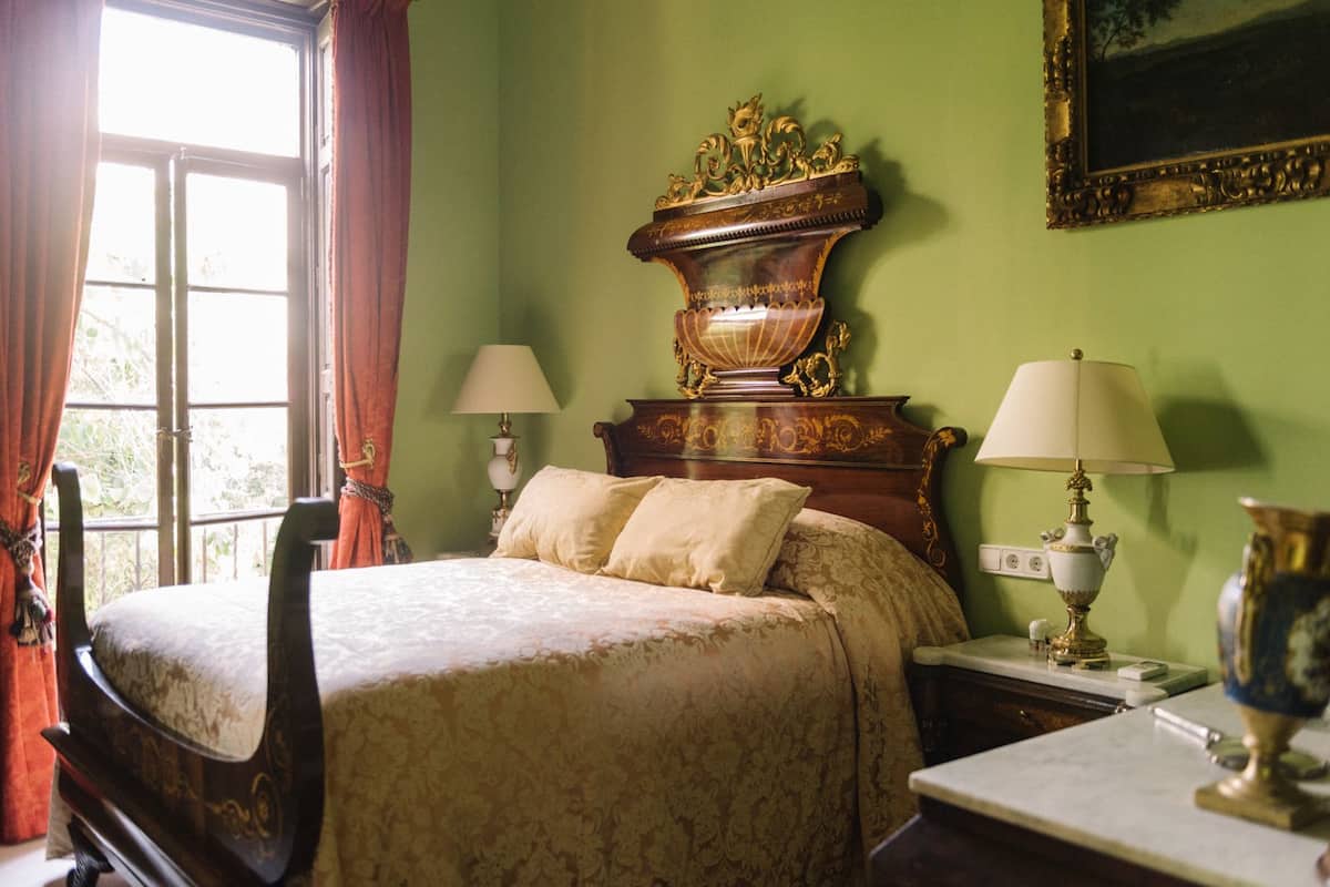 A bedroom with a bed, two bedside tables, a nightstand, a lamp, and a mirror.