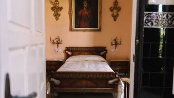 A bedroom with a wooden bed, a painting on the wall, and two wall sconces.