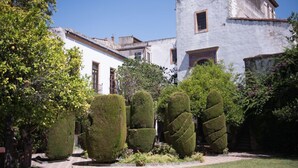 A traditional building with a white facade and a tiled roof, surrounded by well-manicured topiary and a small garden. - Palacio del Virrey Laserna (Jerez de la Frontera)
