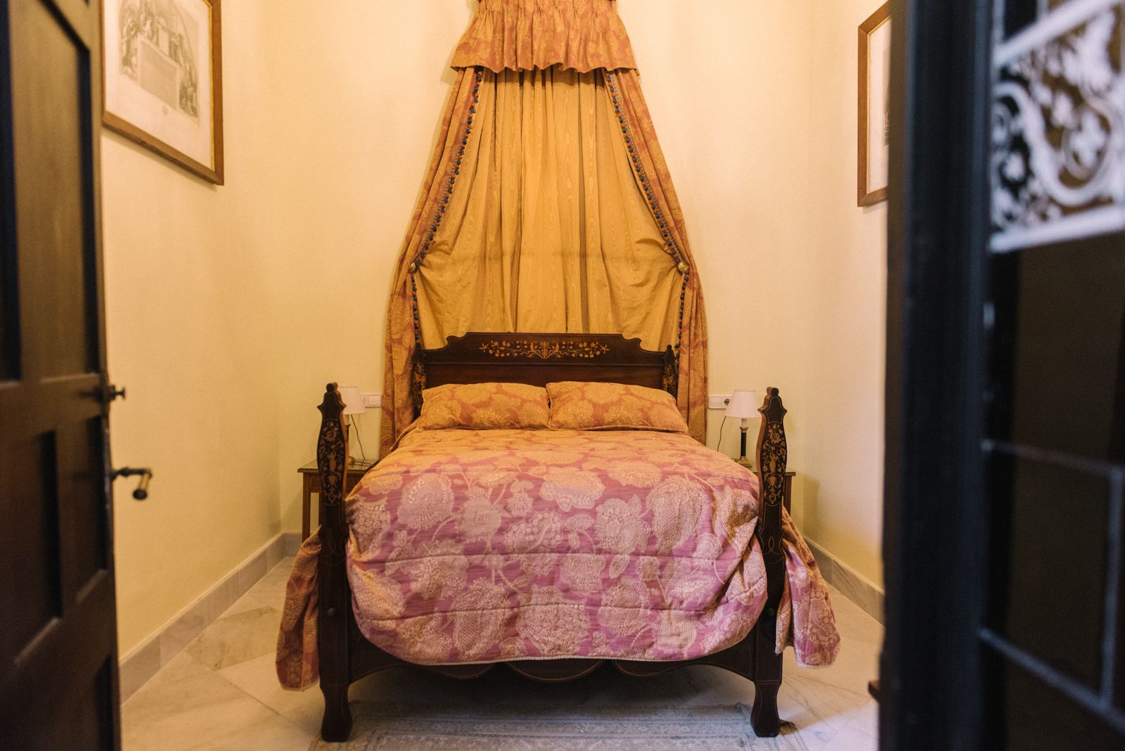 A bedroom with a four-poster bed, a canopy, and a patterned bedspread.