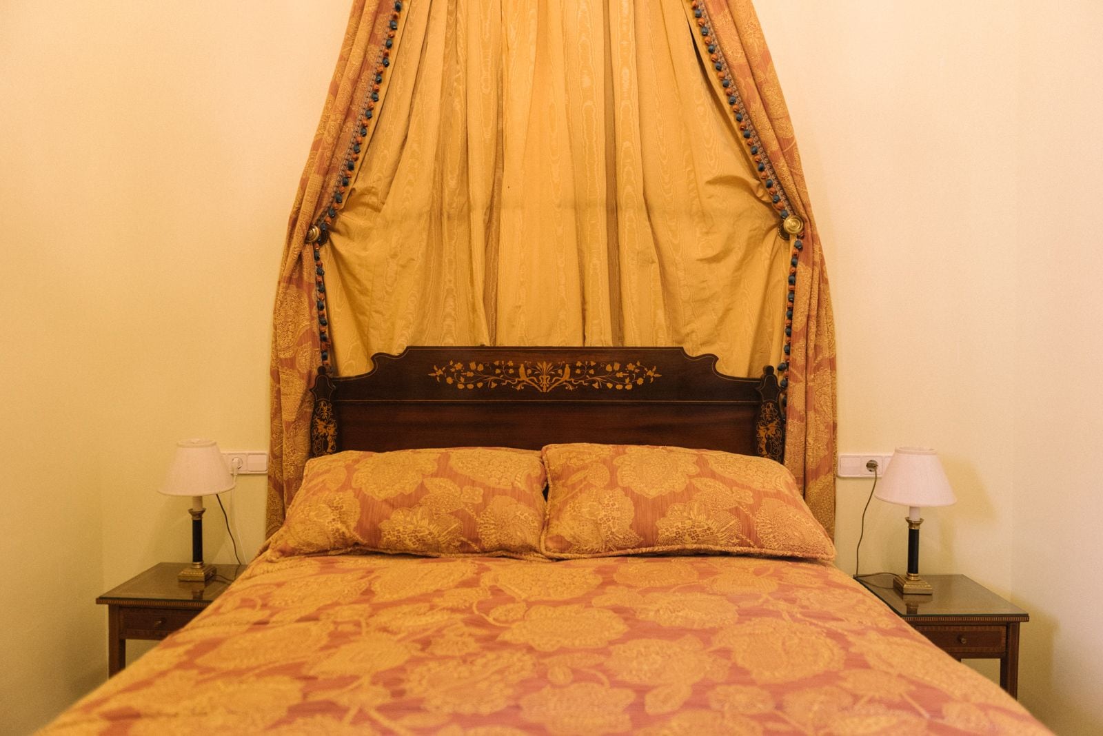 Een bed met hemel, twee nachtkastjes en lampen.