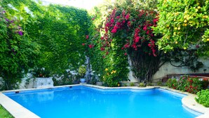 A rectangular swimming pool surrounded by lush greenery and flowering plants. - Palacio del Virrey Laserna (Jerez de la Frontera)