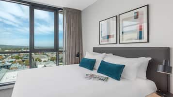 A hotel room with a large bed, a nightstand, a lamp, and two framed artworks on the wall.