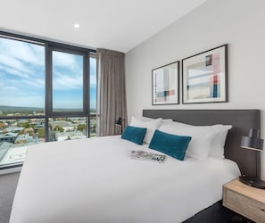 Een hotelkamer met een groot bed, een nachtkastje, een lamp en twee kunstwerken in een lijst aan de muur.