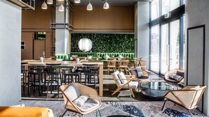 A modern restaurant with high ceilings, hanging pendant lights, and a green wall with a vertical garden.