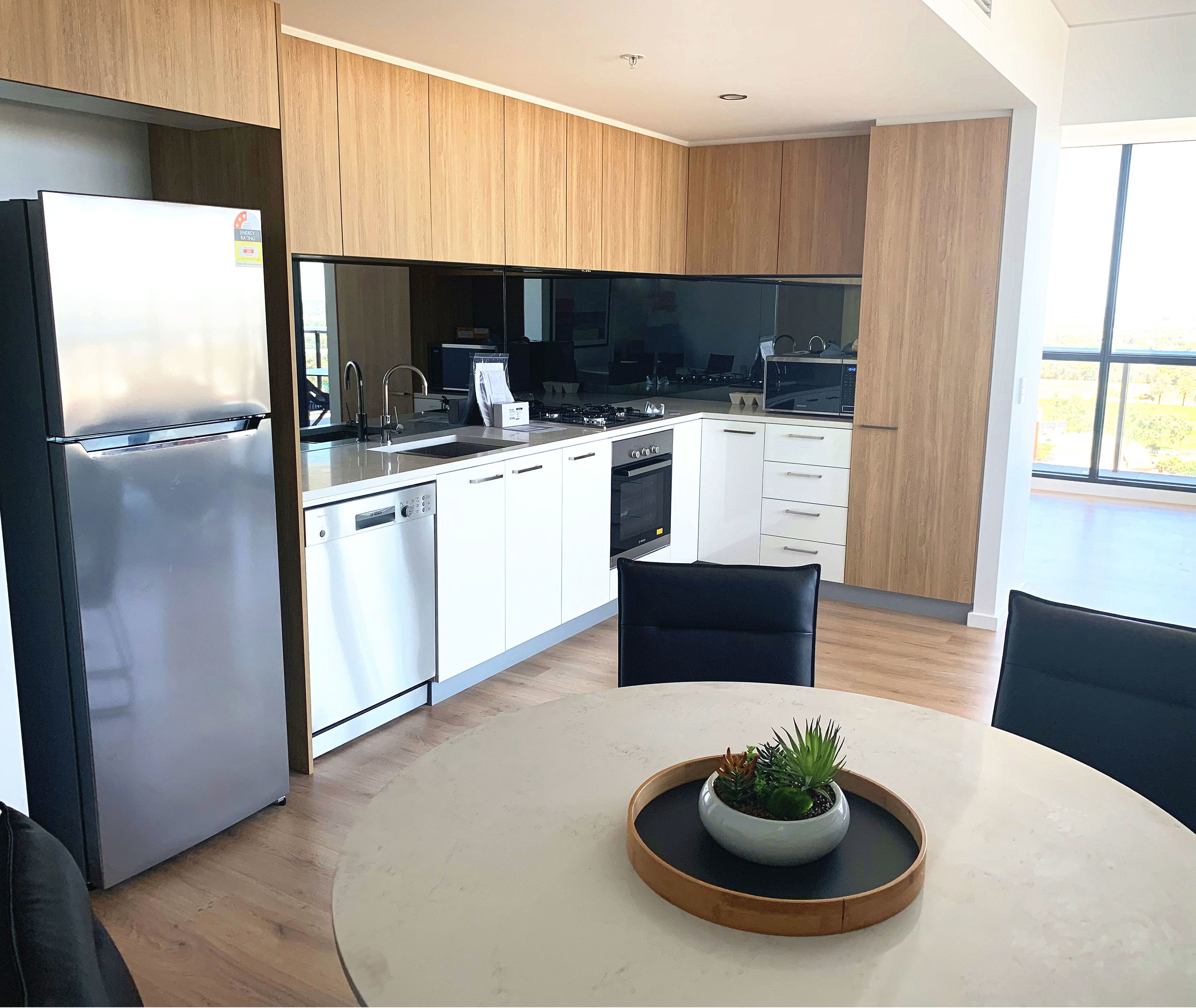 A modern kitchen with white cabinets, stainless steel appliances, and a dining area with a round table and chairs.