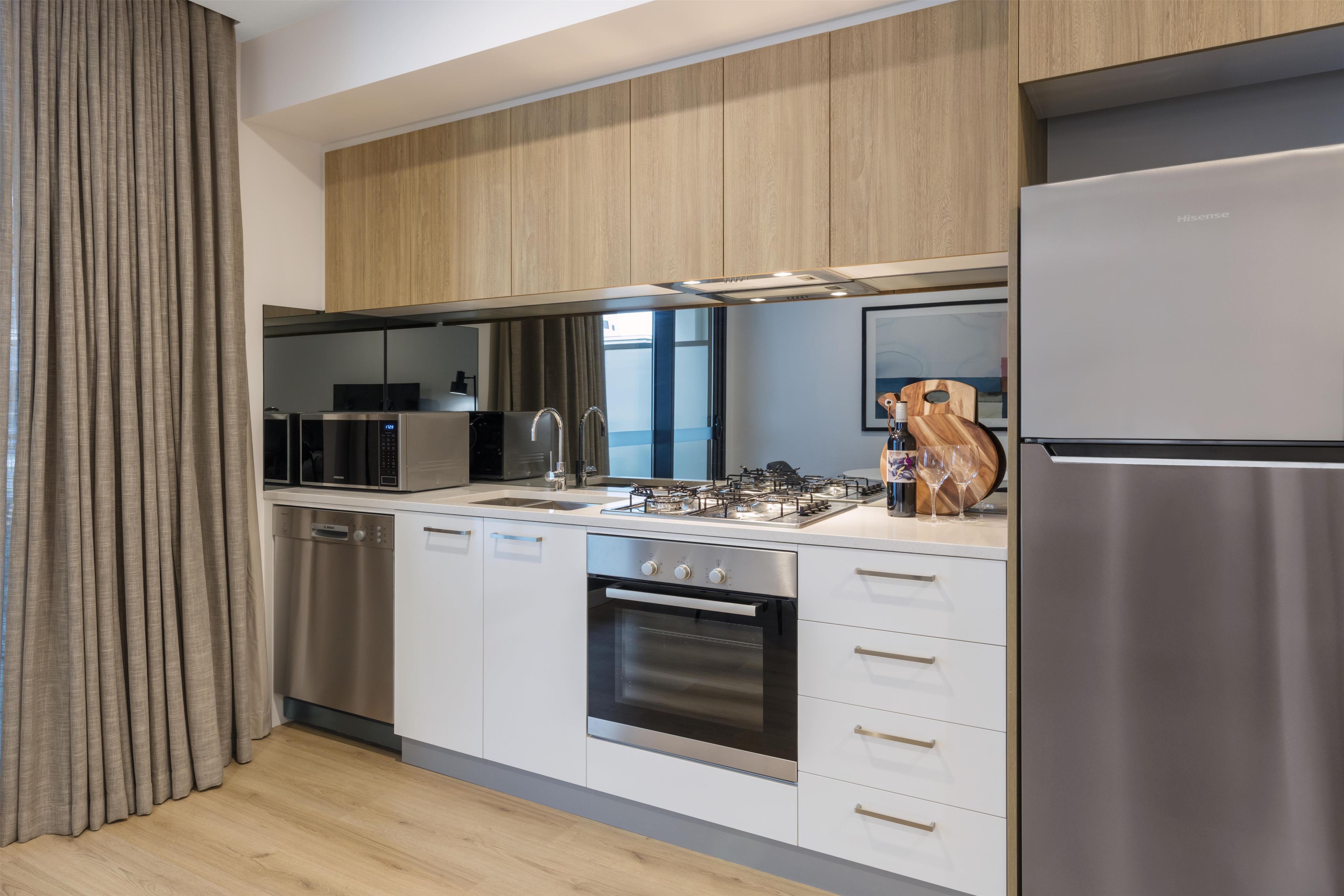 A modern kitchen with stainless steel appliances, a dishwasher, and wooden cabinets.