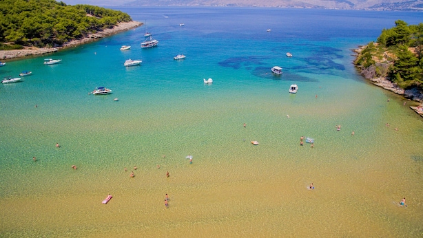 A coastal beach with clear waters, boats, and people swimming. - Villa Miljak (Podstrana)