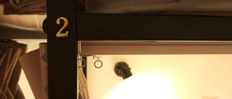 A bunk bed with a visible number '2' on the side, a curtain, and a partially visible room interior with a lamp.