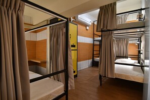 Un dormitorio con literas, suelo de madera y cortinas color beige.