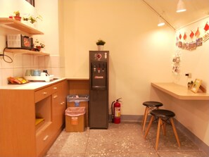 Una cocina compacta con refrigerador, un cesto de basura y extintor.