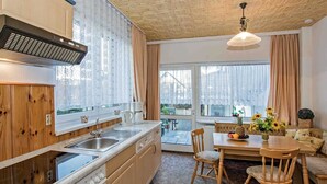 A cozy kitchen with wooden cabinets, a built-in oven, and a window overlooking a garden. - Haus Ückeritz Bauernsuite - Haus Ückeritz Bauernsuite (Ückeritz)