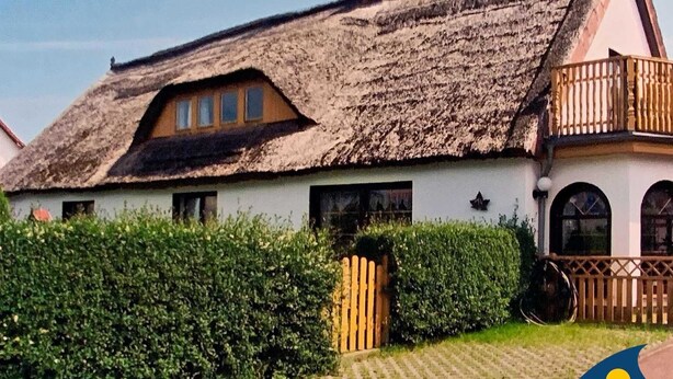 A traditional thatched-roof house with a wooden balcony, a gate, and a hedge in the foreground. - Haus Ückeritz Bauernsuite - Haus Ückeritz Bauernsuite (Ückeritz)