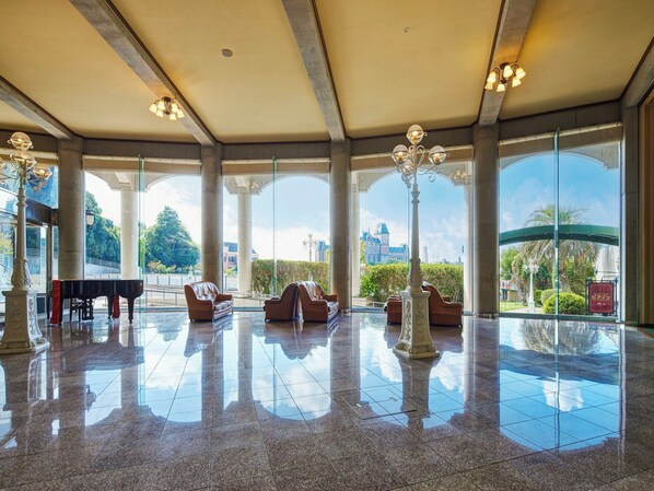 A spacious lobby with large windows, a grand piano, comfortable seating, and a polished floor. - Hotel Lorelei (Sasebo)