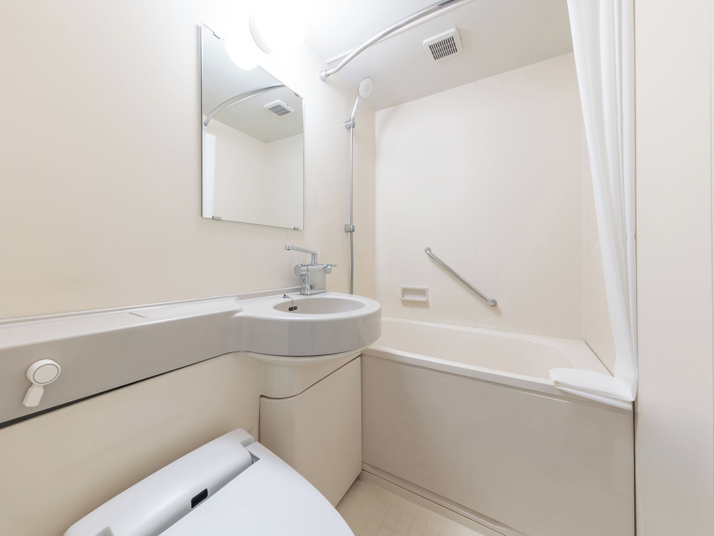 A modern bathroom with a sink, mirror, shower, and grab bar.