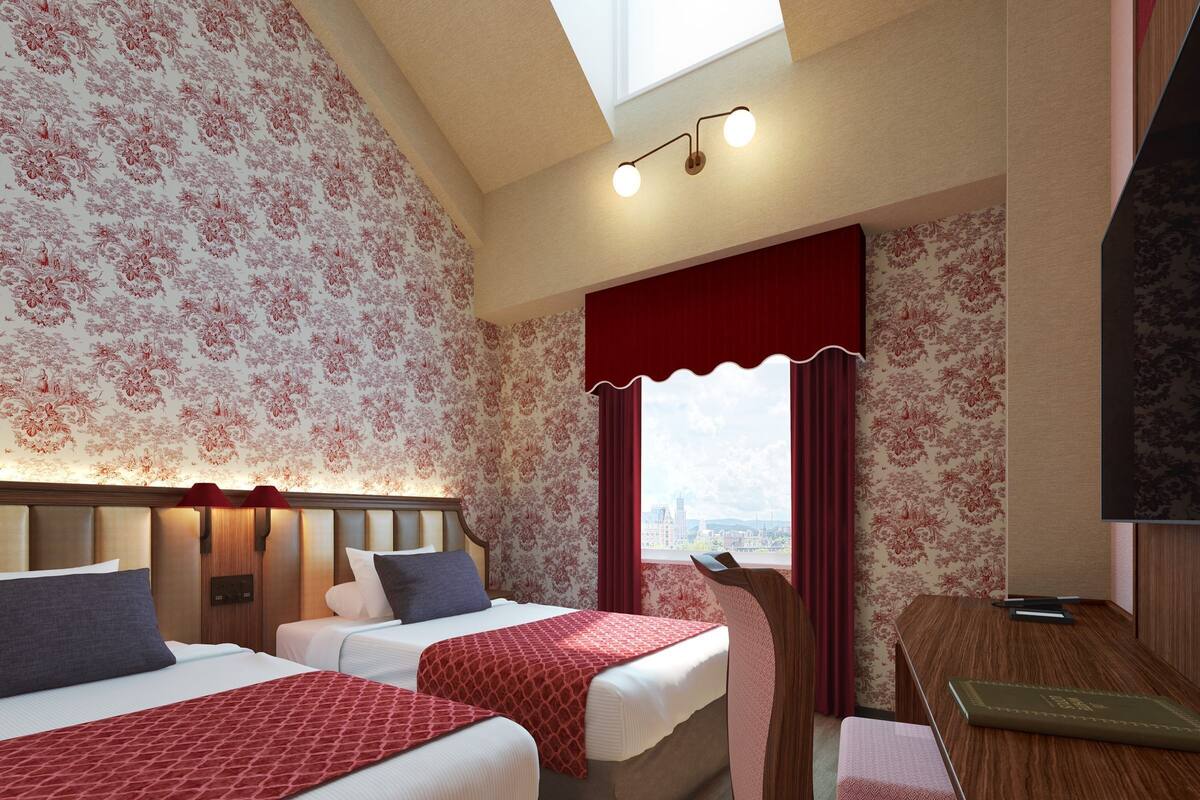 A hotel room with two beds, a desk, a television, and a city view.