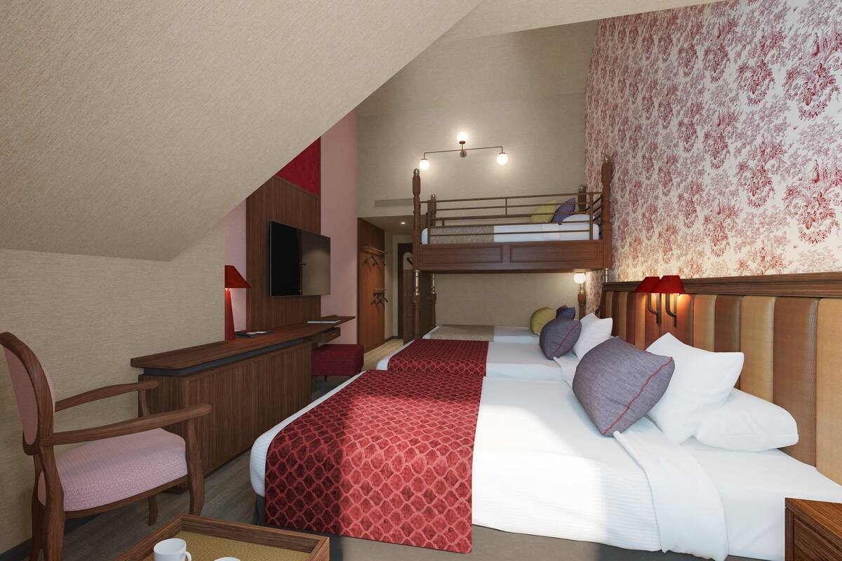 A bedroom with a bunk bed, a desk, a chair, a TV, and a bedside table with a lamp.