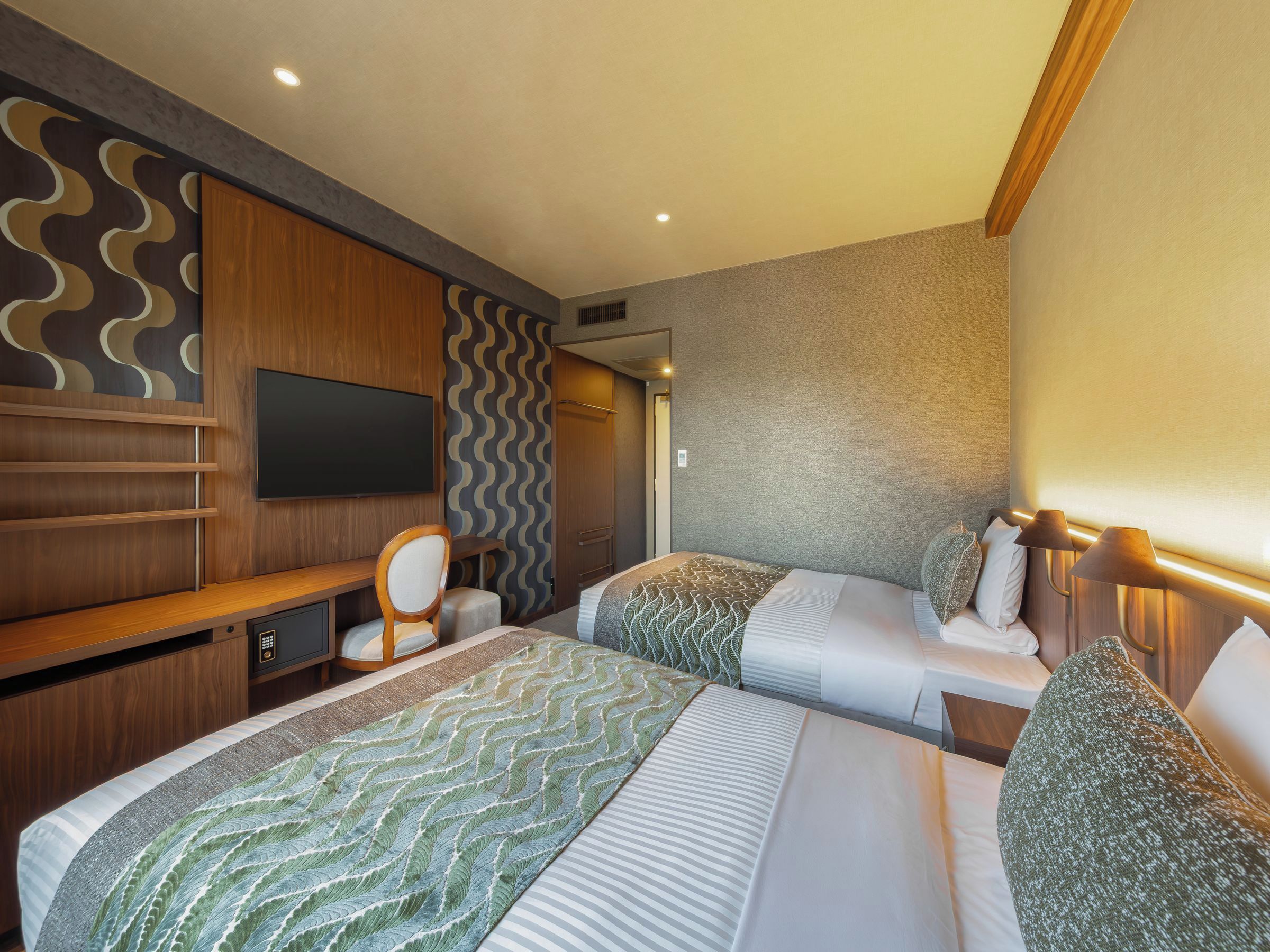 Une chambre d’hôtel comprenant un lit, des tables de chevet, une télévision et un coin salon avec une chaise et une petite table.