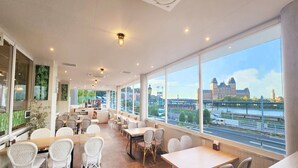 A modern restaurant with large windows offering a view of a cityscape and river. - Hotel Lorelei (Sasebo)