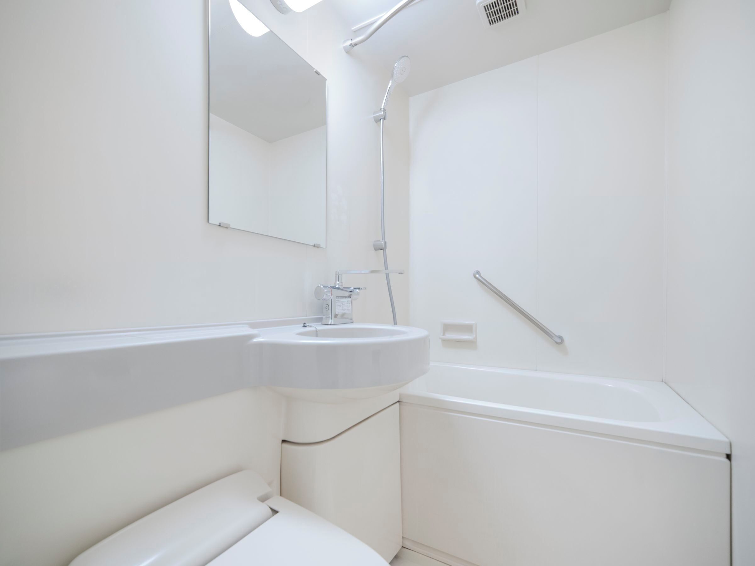 A modern bathroom with a white sink, mirror, and shower.
