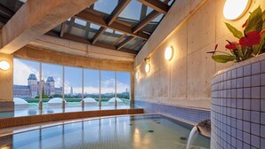 A swimming pool with a view of a cityscape, large windows, and a tiled wall. - Hotel Lorelei (Sasebo)
