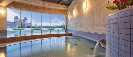 Ein Schwimmbad mit Blick auf eine Stadtlandschaft, großen Fenstern und einer gefliesten Wand.