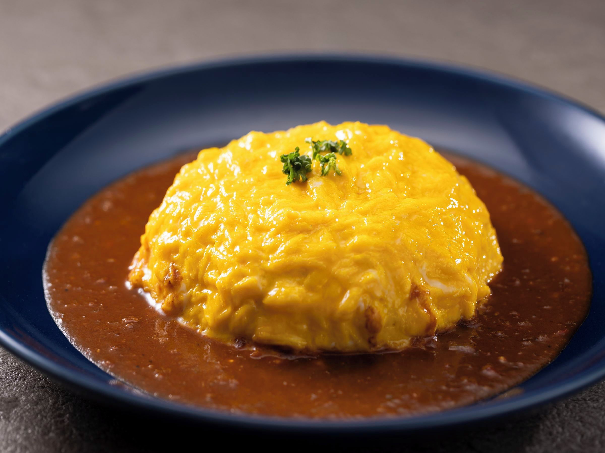 A dish with a golden-brown sauce on a dark blue plate.