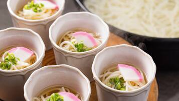 Four bowls of ramen with toppings, a bowl of noodles, and a pot in the background.