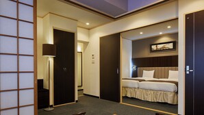A hotel room with a bed, a desk, and a chair. There is a door leading to another room. - Hotel Lorelei (Sasebo)