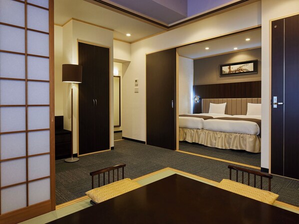 A hotel room with a bed, a desk, and a chair. There is a door leading to another room. - Hotel Lorelei (Sasebo)