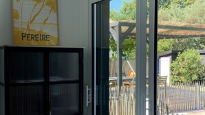 Una habitación con puerta corrediza de vidrio que da a un espacio exterior con terraza de madera y piscina.