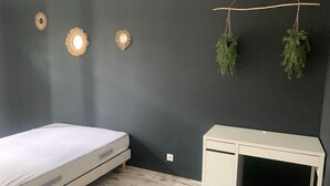 Un dormitorio con cama, escritorio y dos plantas colgantes.