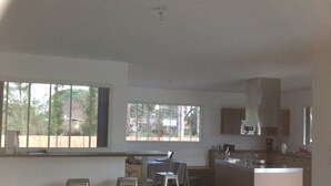 Una cocina amplia con una isla central, ventanas grandes y un comedor con mesa y sillas.