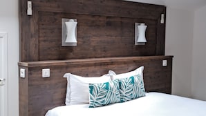 A bedroom with a wooden headboard, white bedding, and a teal leaf-patterned pillow. - Résidence Le Beau Rivage (Bandol)